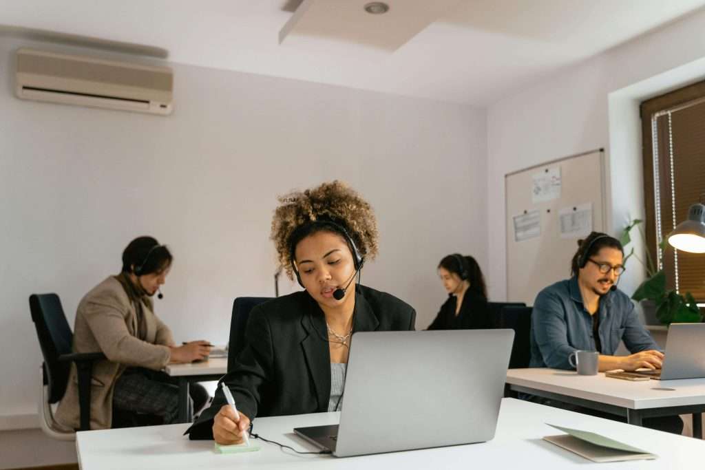 Contractor office team using AI voice receptionists with headsets and laptops to handle calls and schedule jobs efficiently.